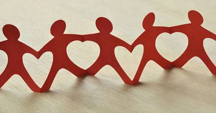 This image shows paper cut-outs of people holding hands