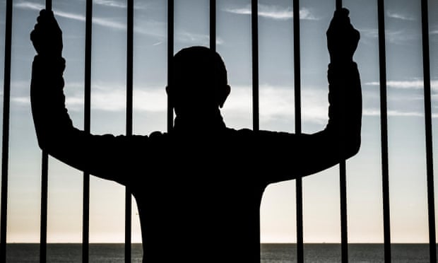 Silhouette of man looking through steel bars