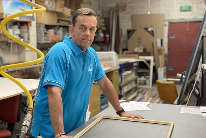 Andrew Kelly stands in his shop in front of a work bench.